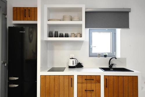 a kitchen with a black refrigerator and wooden cabinets at Beachfront cycladic suite Irene Apartments boutique hotel in Kanala
