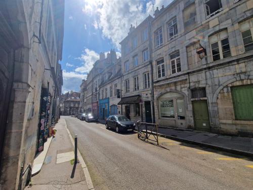 une rue urbaine avec des bâtiments et une voiture garée dans la rue dans l'établissement Le cocon, à Besançon