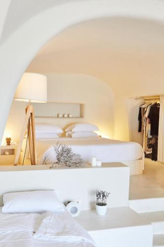 a bedroom with two beds and a table with a lamp at 270 Oias View in Oia