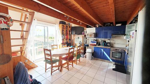une cuisine avec une table et une cuisine avec des armoires bleues dans l'établissement Résidence des Deux Plages, à La Rochelle