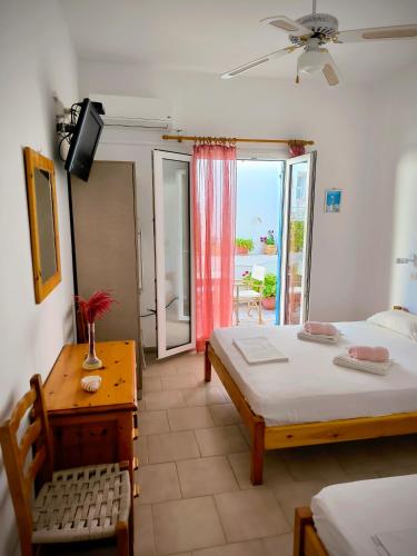 a bedroom with a bed and a table and a window at Dolphin Rooms in Antiparos