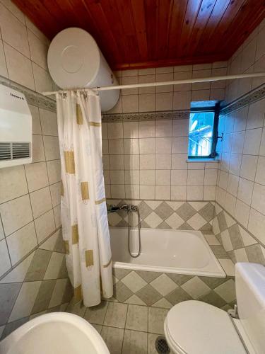 a bathroom with a tub and a toilet and a sink at Petra Maisonettes in Kariá