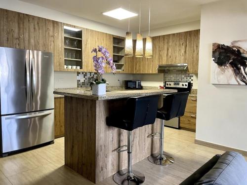 a kitchen with a refrigerator and a counter with stools at Tumon Isa 16 Condo in Tamuning