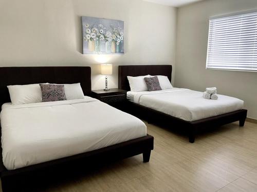 a bedroom with two beds and a table with a lamp at Tumon Isa 16 Condo in Tamuning