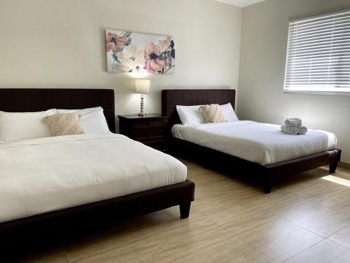 a bedroom with two beds and a table with a lamp at Tumon Isa 16 Condo in Tamuning