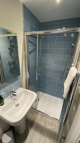 a bathroom with a sink and a shower with blue tiles at East Trayne Holiday Cottages in South Molton
