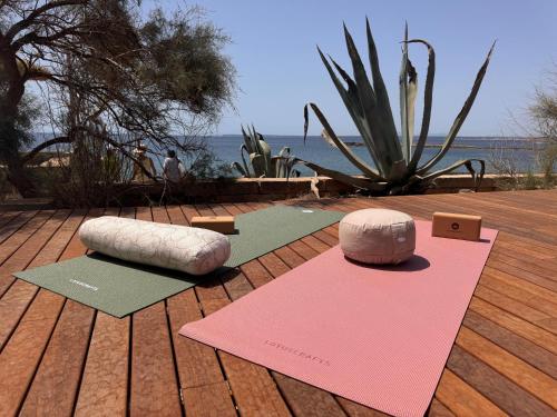 two yoga mats on a wooden deck with the ocean at Bikini Island & Mountain Hotel Es Trenc -Adults only- in Colonia Sant Jordi