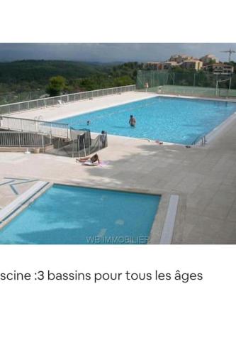 une grande piscine avec des gens dans l'eau dans l'établissement Charmant appartement, Terrasse, Piscine, parking, à Mougins