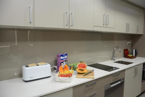 a kitchen with a counter with a toaster and fruits on it at Ratsun Nadi Airport Apartment Hotel in Nadi