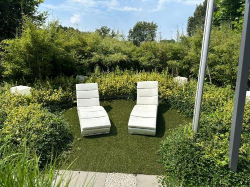 two white chairs sitting on the grass in a garden at Tranquilo Maaseik in Maaseik