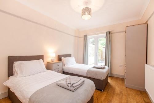 Dos camas en un dormitorio pequeño con ventana. en The Tea House - A Stones Throw From Beach, en Broadstairs