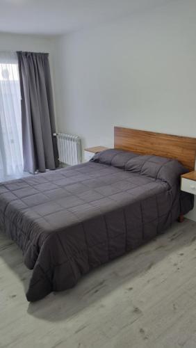 a bedroom with a large bed with a wooden headboard at Depto moderno a estrenar!!! in Comodoro Rivadavia