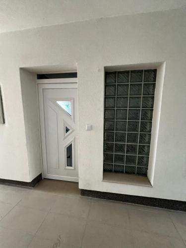 a white door with a window next to a white wall at No1 Apartments in heart of Sarajevo in Sarajevo