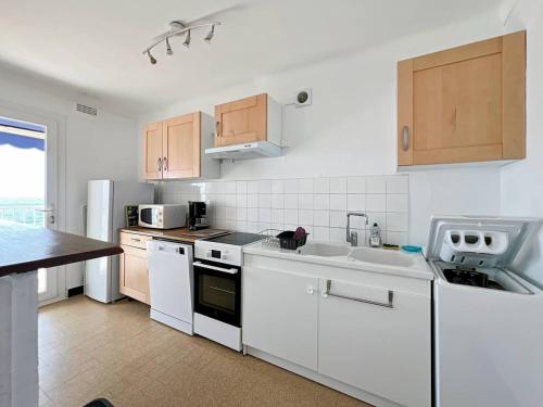 une cuisine avec des appareils électroménagers blancs et des armoires en bois dans l'établissement F3 à Palavas, en bord de mer, pour 4 personnes avec grande terrasse - FR-1-559-31, à Palavas-les-Flots