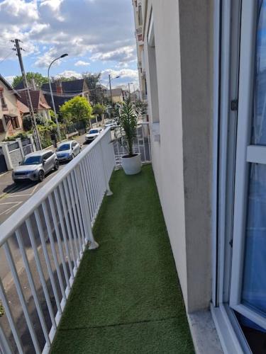 d'un balcon avec une pelouse verdoyante sur le côté du bâtiment. dans l'établissement Appartement à 15 minutes de Paris et Parc Expositions de Villepinte de CDG, à Aulnay-sous-Bois