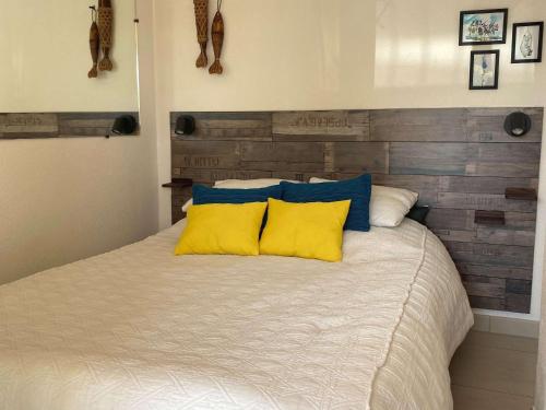 - un lit avec des oreillers jaunes et bleus dans l'établissement Agréable T2 climatisé avec Loggia, Parking, et Wifi à Balaruc-les-Bains - FR-1-553-250, à Balaruc-les-Bains