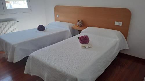 two beds with white sheets and purple flowers on them at Hotel Victorino in Silleda