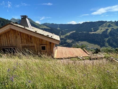 an old house on a hill with mountains in the background at Chalet Morzine in Morzine