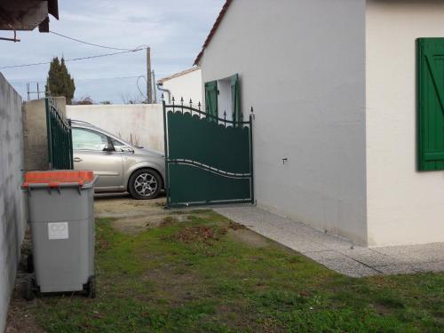 a car is parked next to a green gate at les cossonnettes calmes et agréables in La Couarde-sur-Mer