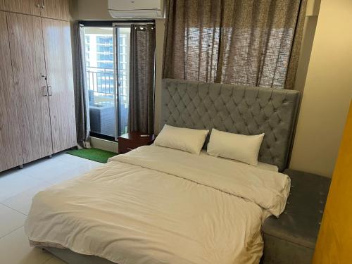 a bedroom with a large bed and a large window at DHA The Terrace Loft 3 Bedrooms AQZ Apartments in Islamabad