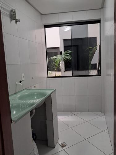 a bathroom with a green sink and a window at Dois quartos Cozinha completa Wi Fi Self check in com senha Central e perto de tudo a 4,4Km da Rodoviária e 15,4Km do Aeroporto Apartamento 101 in Vitória da Conquista
