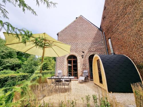 FernelmontにあるGîte de la Ferme de Seron - gîte de charme à la campagne avec saunaのパティオ(テーブル、黄色い傘付)