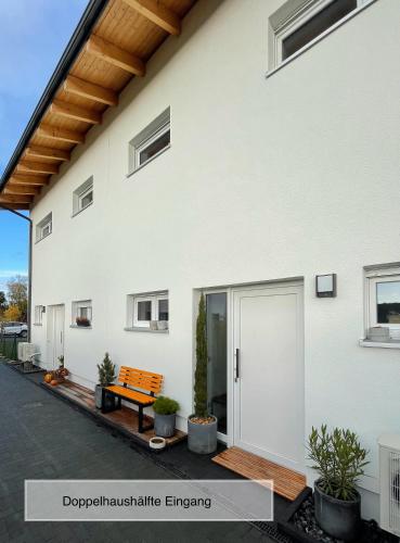 a white house with a bench in front of it at Moderne Doppelhaushälfte mit 3 SZ in der Nähe vom Scharmützelsee-seperat&naturnah in Wendisch Rietz