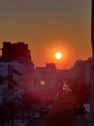 une rue de la ville avec le soleil couchant dans le ciel dans l'établissement Appartement vue Marie Vincennes, à Vincennes