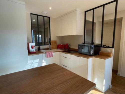 une cuisine avec des armoires blanches et un micro-ondes dans l'établissement Appartement Skylar, à Dinan