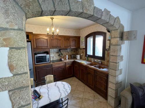 une cuisine avec une arche en pierre avec une table à l'intérieur dans l'établissement Maison proche des plages, à Théoule-sur-Mer