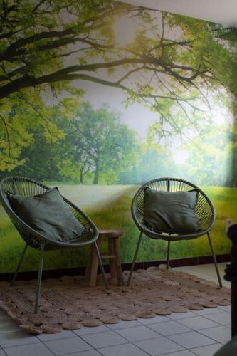 two chairs in front of a wall with a painting at Doornhof, rustig gelegen vakantiehuis in Haaltert