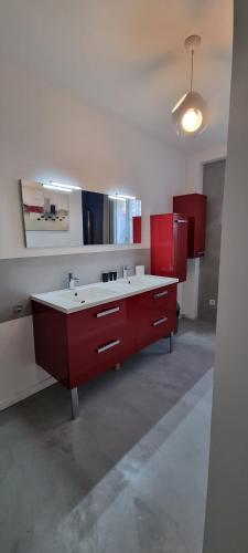 une salle de bain avec un lavabo rouge et des armoires rouges dans l'établissement Maison proche mer, à Pleurtuit