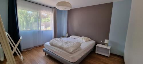 une chambre avec un lit avec une grande fenêtre dans l'établissement Maison proche mer, à Pleurtuit