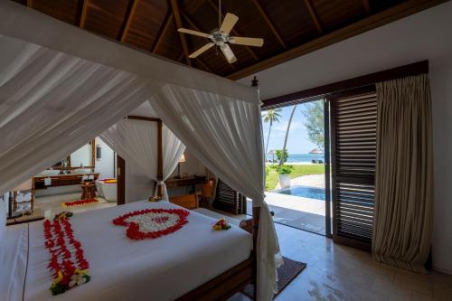 a bedroom with a bed with a ceiling fan at The Residence Zanzibar in Kizimkazi