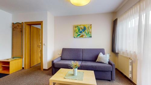 a living room with a blue couch and a table at Café Pension Heim in Kirchberg in Tirol