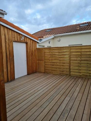 a garage with a wooden fence and a building at Chambre privée dans maison d’hôtes in Cenon