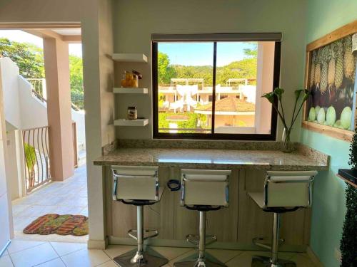 a kitchen with two bar stools and a window at Discounted - Puravida Escape And Rooftop Terrace in Coco