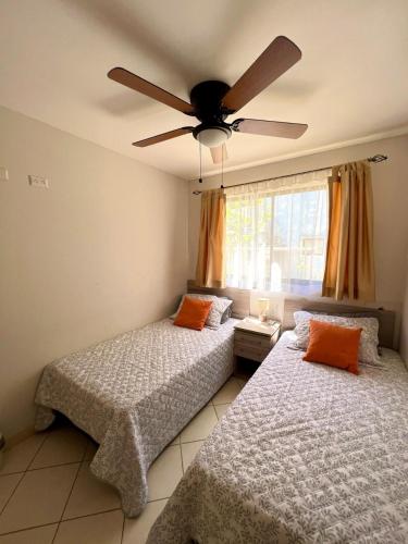 two beds in a bedroom with a ceiling fan at Beach Dreams Coco - 60 meters from Beach in Coco