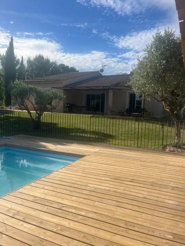 une cour avec une piscine et une terrasse en bois dans l'établissement Maison du paty, à Piolenc