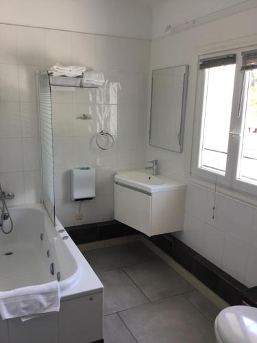 une salle de bain blanche avec une baignoire et un lavabo dans l'établissement Le Jardin des Oliviers, à Sigean
