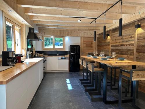 une grande cuisine avec une longue table et des murs en bois dans l'établissement Chalet confortable avec cheminée et terrasse à Samoëns - FR-1-624-5, à Samoëns