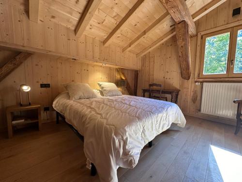 une chambre avec un grand lit dans une pièce avec des plafonds en bois dans l'établissement Chalet confortable avec cheminée et terrasse à Samoëns - FR-1-624-5, à Samoëns