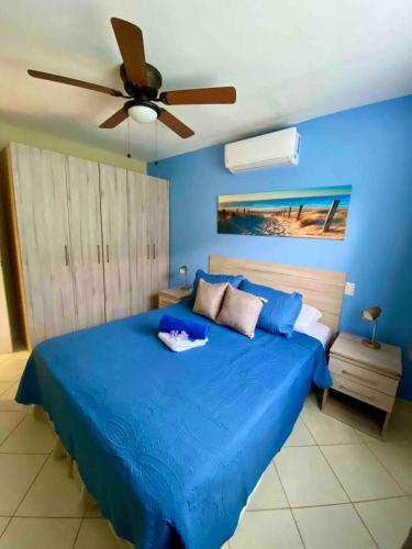 a bedroom with a blue bed with a ceiling fan at Sun and Waves Getaway in Coco