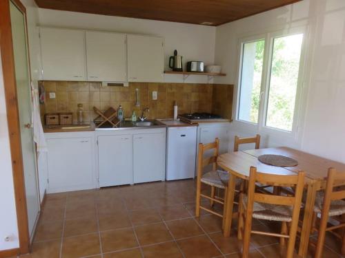 une cuisine avec des armoires blanches et une table et des chaises dans l'établissement Calme et tranquillité en Vallée d'Ossau, à Bilhères en Ossau