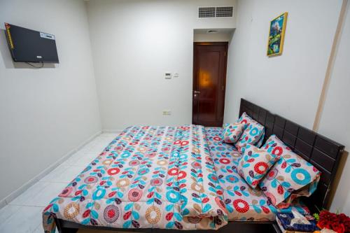 a bedroom with a bed with a colorful comforter and pillows at tourist Family and couple private Rooms ME11 BGR 01 baith al jannah LLC one private room in three bedroom apartment in Abu Dhabi