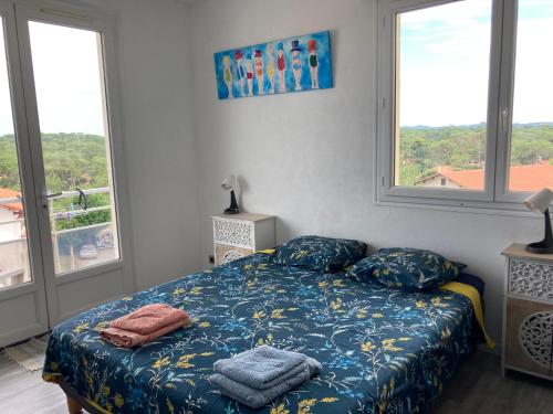 - une chambre avec un lit doté de draps bleus et de fenêtres dans l'établissement Face Mer 2 chambres parking, à Soorts-Hossegor
