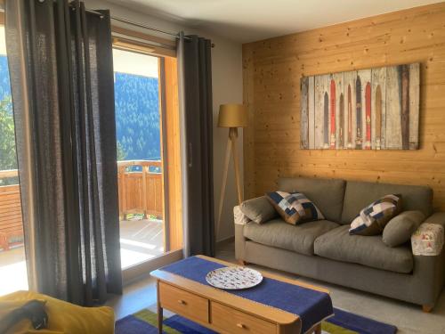 un salon avec un canapé et une grande fenêtre dans l'établissement Appartement 4 personnes Bee on skis à Oz en Oisans, à Oz