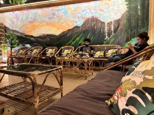 a group of people sitting in chairs in front of a mural at Forrest Hostels in Mumbai