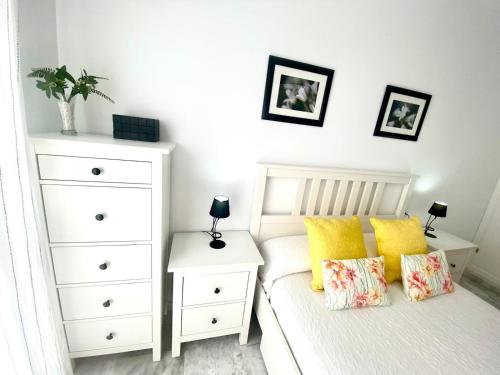 a bedroom with a white bed with yellow pillows at Apartamento Atlántico in Rota