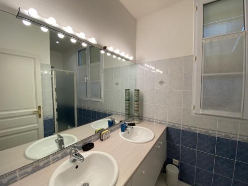 une salle de bain avec deux lavabos et un grand miroir dans l'établissement Maison familiale 100m de la plage 